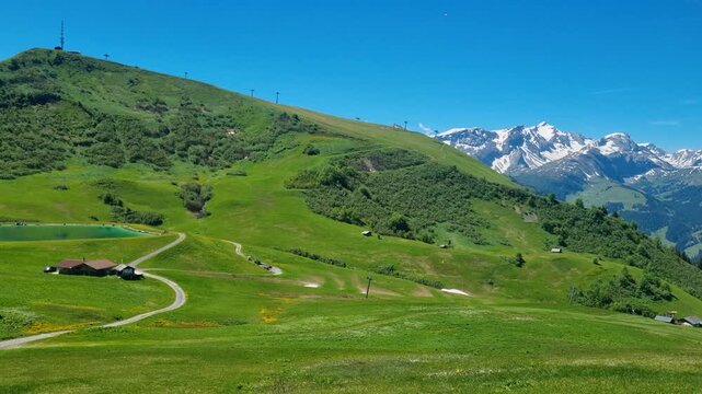 Panoramic view from Hahnenmoos in the Bernese Oberland, overlooking Metschstand and snow-capped peaks. Alpine summer meadow, clear blue sky, sunny Swiss hiking paradise