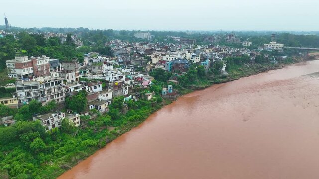 Muddy monsoon waters of the Tawi River threatening flood prone housing due to poor urban planning in Jammu.