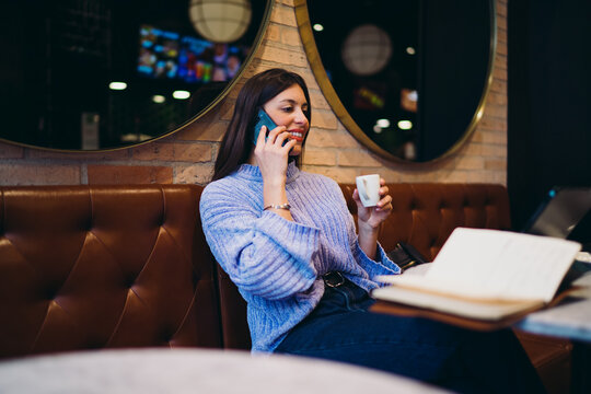 Happy woman talking on smartphone while enjoying coffee in cafe, taking break from remote work with tablet, mobile conversation, roaming service, digital nomad lifestyle, authentic scene