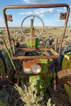 The steering wheel on the rusty frame of an abandoned tractor