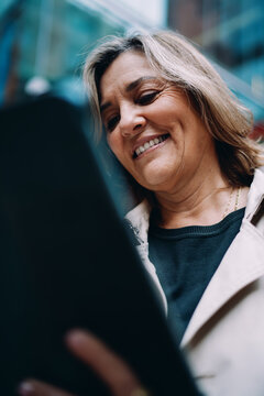 Happy mature woman looking down at tablet screen, close up portrait of female user browsing internet, digital inclusion, tech for seniors, social networking, authentic representation, copy space