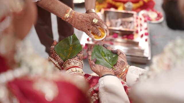Close up of priest applying tilak on betel leaves at wedding