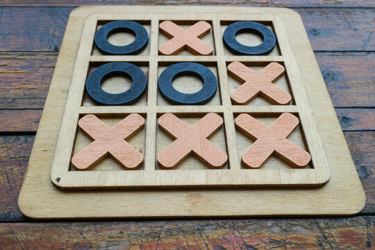 Close up of a vintage wooden tic tac toe board game on a rustic table. A winning strategy concept perfect for business problem solving, educational leisure, and brain teasers.