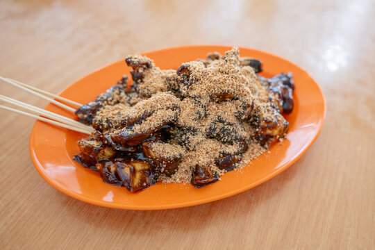 A plate of rojak covered in thick sweet dark sauce and crushed peanuts.