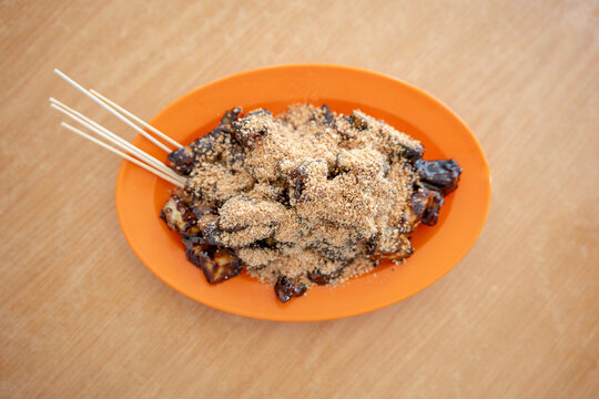 A plate of rojak covered in thick sweet dark sauce and crushed peanuts.