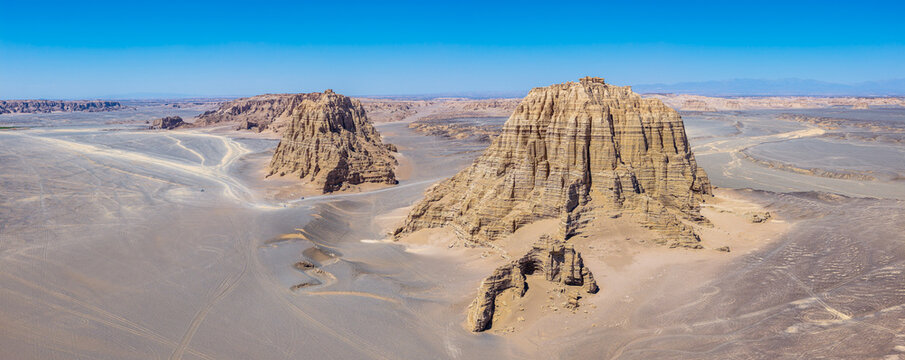 Two giant clay rock towers in a yardang desert landscape under a blue sky in the Gobi Desert, Dahaidao, Xinjiang, China