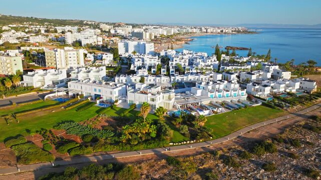 Drone view of Protaras, Cyprus seaside hotels. Rocky coastline, resort buildings and clear blue water create a scenic coastal travel view.