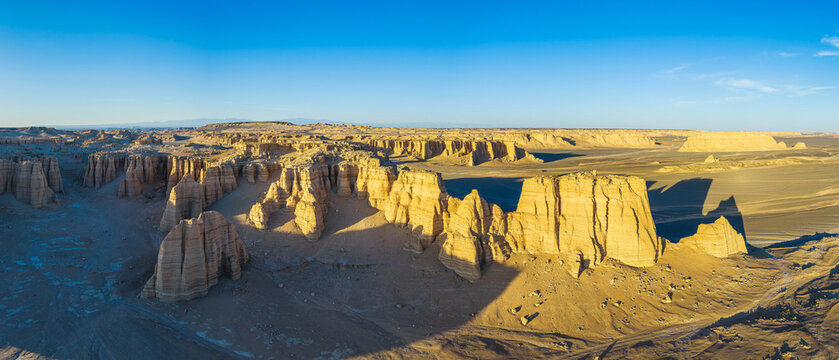 Aerial view of golden yardang landforms and sandstone towers in the desert at sunset, Dahaidao, Xinjiang, China