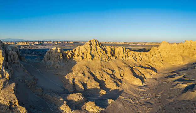 Aerial view of golden yardang landforms with massive sandstone cliffs in the desert at sunset, Dahaidao, Xinjiang, China