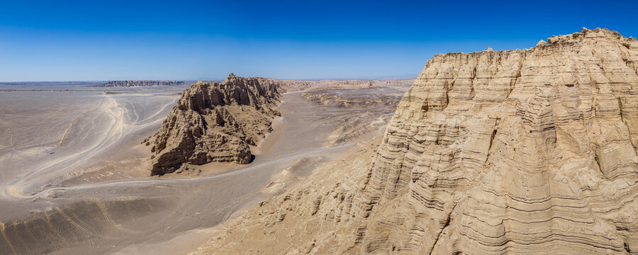 Yardang landform with dry clay cliffs and sand dunes under a clear blue sky in Dahaidao, Gobi Desert, Xinjiang, China