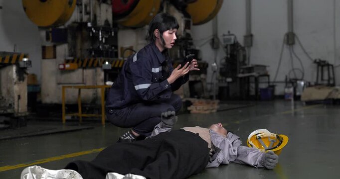  Worker helping injured colleague who collapsed on the floor after accident in factory