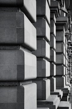 Black and white close up view of heavy rusticated stone block wall facade with repeating pillars in perspective in Indonesia