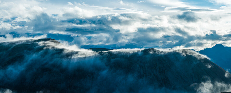 Dramatic view of low clouds rolling over a dark mountain ridge and a sea of clouds, Sichuan, China