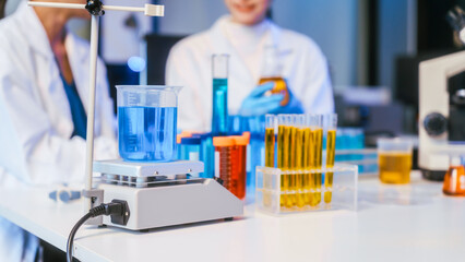 Fototapeta premium Laboratory scene with scientists, beakers and test tubes filled with colorful liquids on a research table.