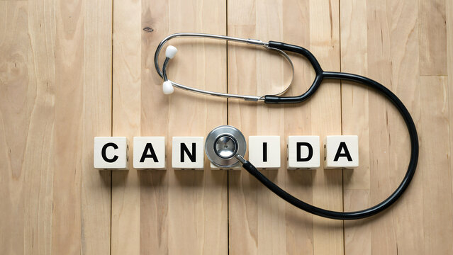 Medical stethoscope placed over wooden cubes spelling the word candida
