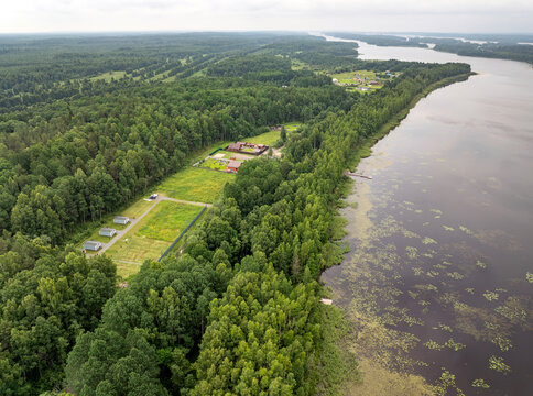 Aerial view of a small holiday resort and sub-divided land plots by a quiet forest lake on an overcast summer day in Karelia, Russia