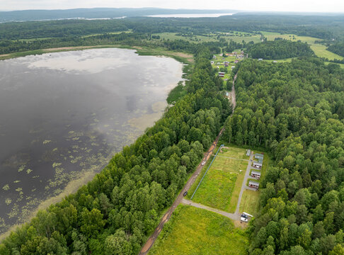 Aerial view of a small holiday resort and sub-divided land plots by a quiet forest lake on an overcast summer day in Karelia, Russia