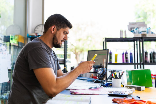 Workshop owner using smartphone managing business activities