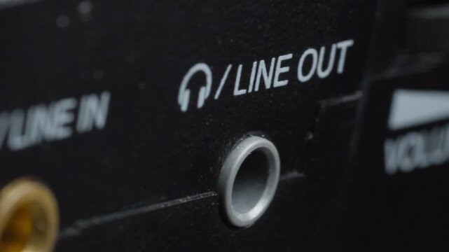 Macro close up showing line out audio connector beside line in port on electronic device with shallow depth of field highlighting analog sound interface and connection details