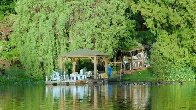 Lakeside wooden gazebo and dock surrounded by green trees