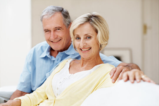 Smile, love and portrait with old couple on sofa for bonding, connection and marriage. Retirement, happy and commitment with senior man and woman in living room in house for relax, trust and care