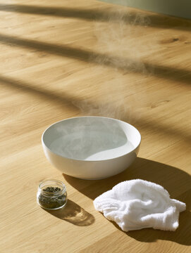 Soaking foot bowl steaming water white towel herbal salt wooden floor spa still life minimal home sunlight shadow clean interior calm mood