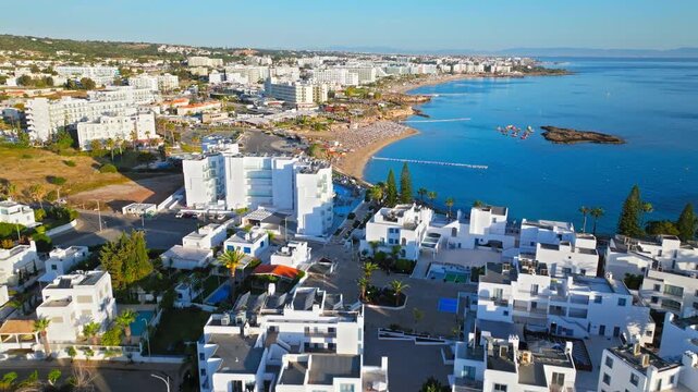 Aerial view of Protaras beach and harbour in Cyprus. Sandy shore, boats, turquoise sea and waterfront buildings create a relaxing summer scene.