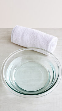 Clear glass bowl white towel light wood minimalist surface top view empty space clean spa relaxation still life