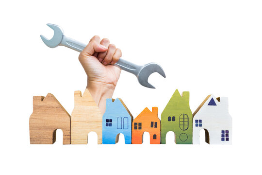 Miniature wooden house collections with open end wrench in hand isolate on white background, building and architect concept, property and real estate industry