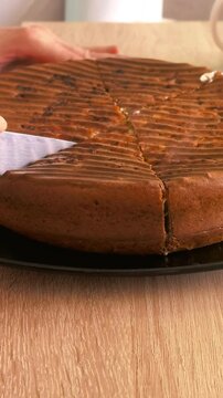 Person cuts a homemade keto pie into slices on a wooden table, low carbohydrate baking, healthy dessert, ketogenic diet, home cooking.