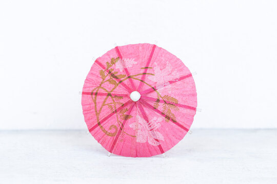 Pink paper umbrella with space on white background, tropical summer decoration item