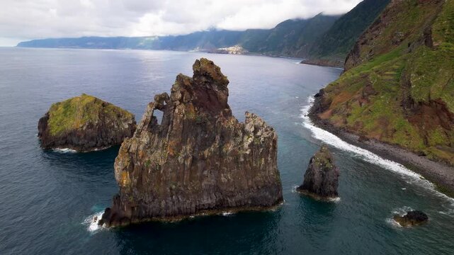 Ribeira da Janela Madeira Portugal Aerial Drone Sideways Track Flight and Orbit Around Sea Stack Rock with Natural Window Hole on Wild Pebbled Beach Coastline Atlantic Travel Video 4K UHD