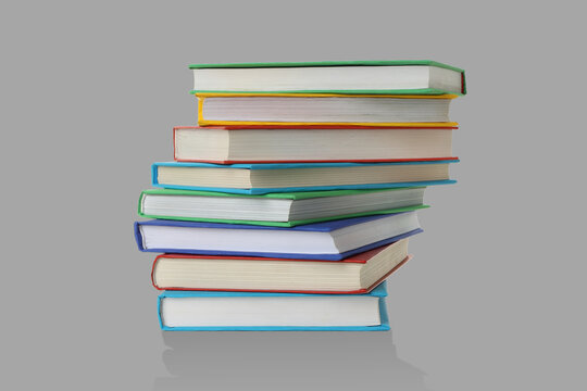 Books are arranged in a stack on a grey backdrop