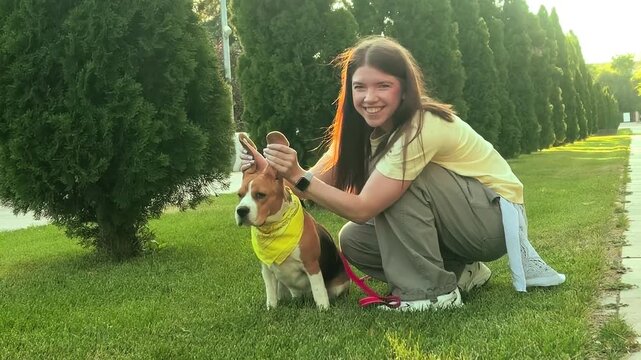 Playful female owner makes funny bunny ears with her beagle dog outdoors, humorous pet interaction, animal companionship, joyful lifestyle moment.