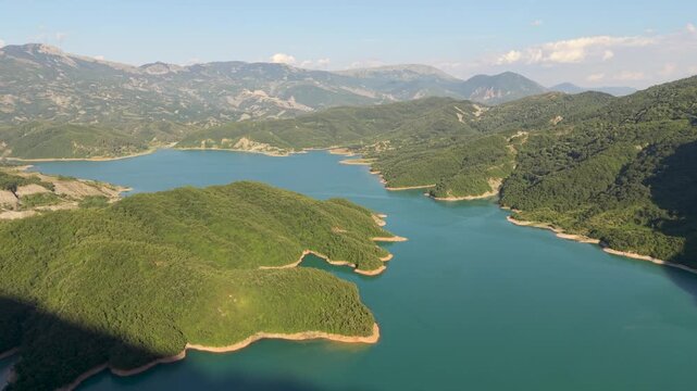 Albania boasts the stunning Bovilla Lake, a peaceful oasis embraced by lush green hills and a vibrant blue sky.