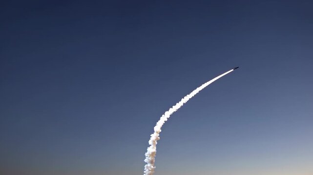 Rocket ascending into the sky, leaving a trail of smoke as it curves upward against a clear blue backdrop, showcasing the power of aerospace technology and engineering