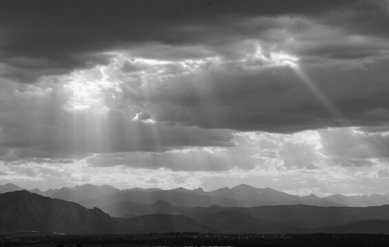 panoramic black and white photo of striking sunset with crepuscular rays over  the boulder flatirons and the front range of the colorado rocky mountains, as seen from broomfield, colorado