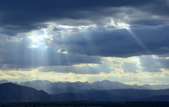 striking sunset with crepuscular rays over  the boulder flatirons and the front range of the colorado rocky mountains, as seen from broomfield, colorado