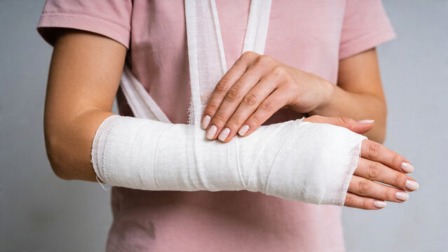 Person holding a bandaged arm after an injury in a simple indoor setting