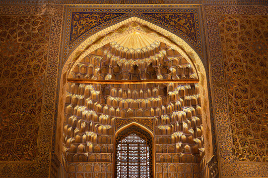 Gilded muqarnas vault inside Gur-e-Amir mausoleum in Samarkand, Uzbekistan. Intricate Islamic geometric patterns and golden ornamentation fill the interior arch. Ideal for travel publications.