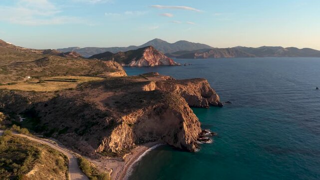 Discover the mesmerizing cliffs and serene waters of Milos, Greece as the sun sets, creating a colorful horizon. Experience the beauty of nature and the charm of this Cycladic paradise
