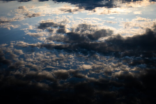 Brooding sky reflects in dusky water with rolling texture and depth. The lake becomes a canvas of light and shade that invites pause wonder and a return to quiet moments of observation.