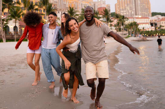 Happy young people embracing the beach lifestyle, dancing barefoot in the sand, celebrating freedom