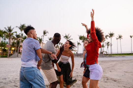 Energetic friends celebrating a summer party on the beach at sunset, embodying the carefree vacation