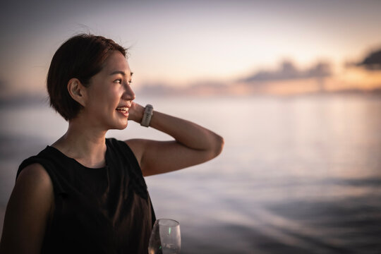 Happy woman enjoys a drink watching the sunset