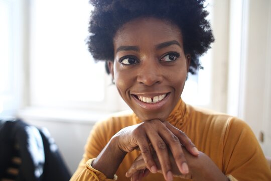 Smiling young black woman rests chin on hands