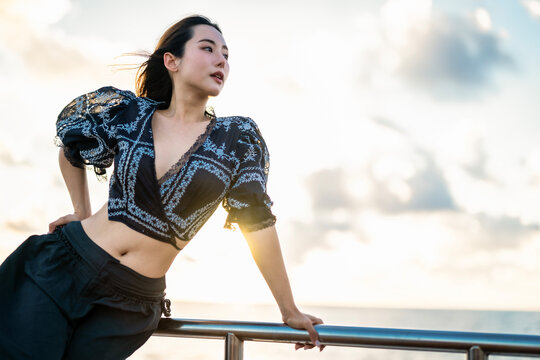 Young Asian woman watching the sunset by the ocean