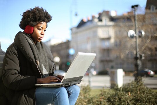 Young Black woman using laptop computer outdoors