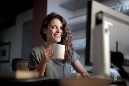Happy young woman enjoying coffee at her desk