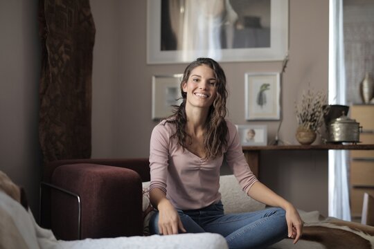 Cheerful woman smiling at camera in living room
